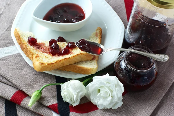 Sweet cherry jam, toast and flowers — Stock Photo, Image