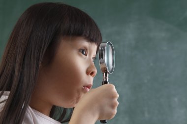 Close up of child holding a magnifier clipart