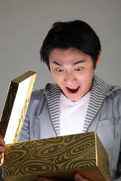 Homem surpreso abrindo uma caixa brilhante — Fotografia de Stock