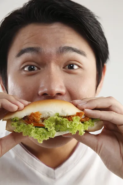 Homem comendo hambúrguer no fundo branco — Fotografia de Stock