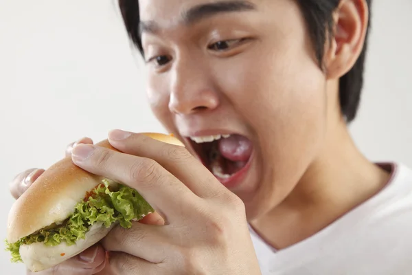 Чоловік їсть бургер на білому тлі — стокове фото