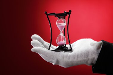 Man with the white hand glove holding an hour glass clipart