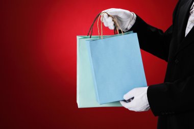 Doorman wearing white gloves, holding shopping bags clipart