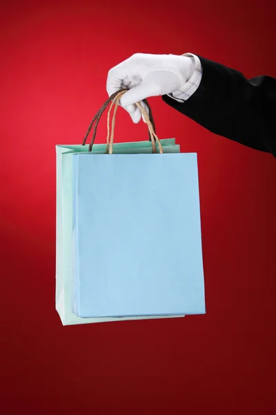 Doorman wearing white gloves, holding shopping bags — Stock Photo, Image