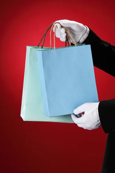 Pförtner trägt weiße Handschuhe, hält Einkaufstüten in der Hand — Stockfoto