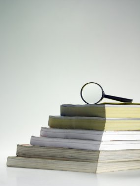 Stack of books and magnifier clipart