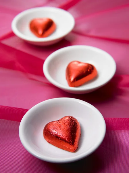 Três chocolate em forma de coração vermelho no pequeno prato — Fotografia de Stock