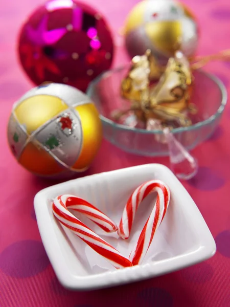 Riet van het suikergoed op de plaat en Kerstmis bal als achtergrond — Stockfoto