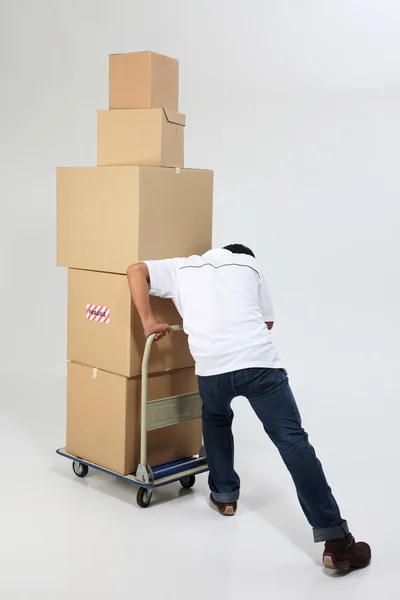 stock image Delivery man pushing a trolley with boxes