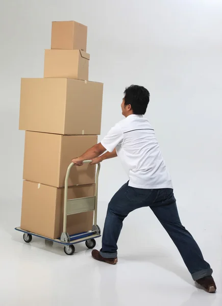 Delivery man pushing a trolley with boxes — Stock Photo, Image