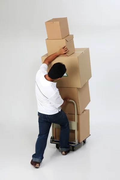 stock image Delivery man struggling to carry moving boxes.