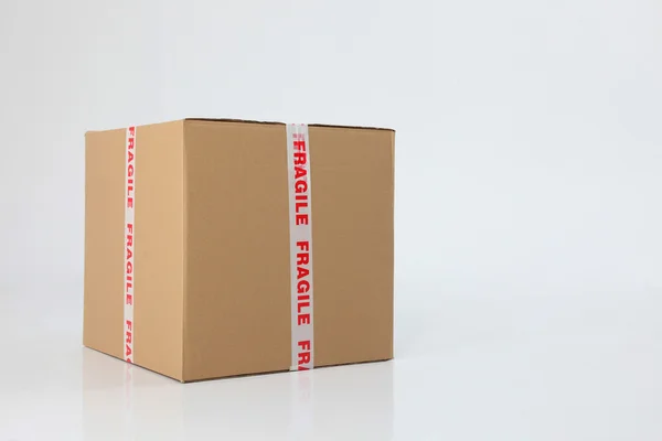 Коричнева картонна коробка запечатана крихким знаком — стокове фото