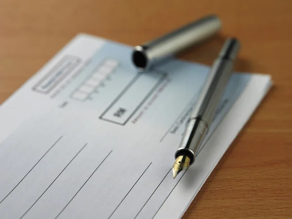 Primo piano di una penna su un libretto di assegni su sfondo bianco — Foto Stock