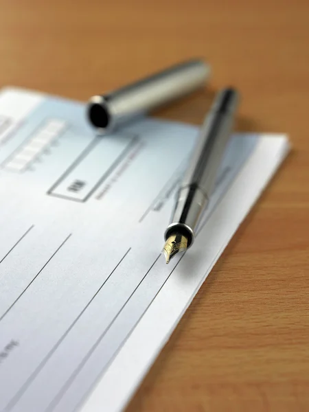 Closeup of a pen on a cheque book on white background — Stock Photo, Image