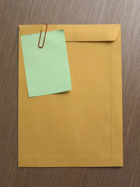 Opmerking op de grote bruine envelop op het tafelblad — Stockfoto