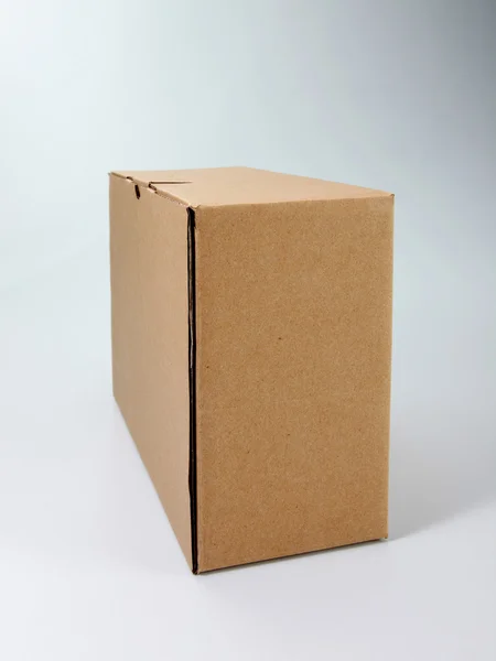 Caja de cartón de color marrón en el fondo de color liso —  Fotos de Stock