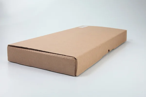 Caja de cartón de color marrón en el fondo de color liso — Foto de Stock