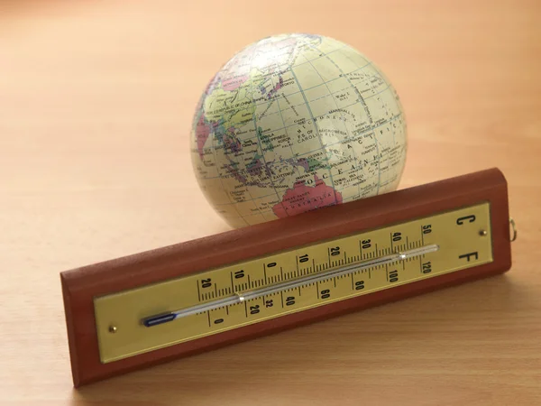 Thermometer in front of the deskglobe — Stock Photo, Image