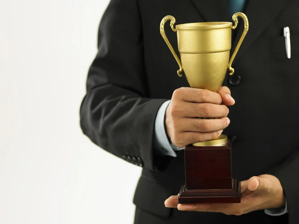 Um vencedor com terno segurando um troféu — Fotografia de Stock