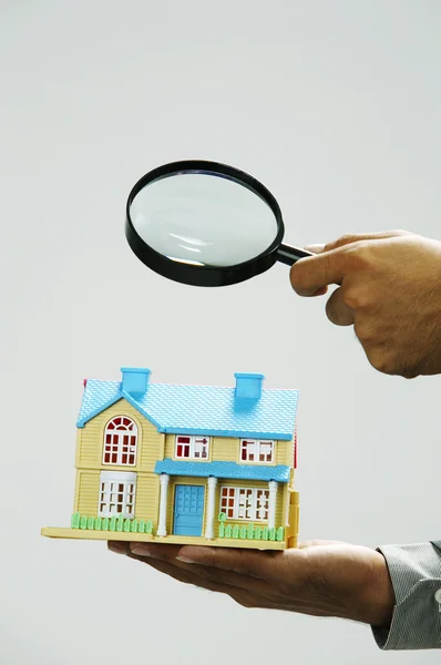 Агент по недвижимости держит увеличитель фокус на модельный дом — стоковое фото