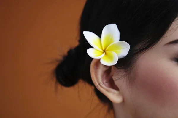Close up on frangipani on woman's ear — Stock Photo, Image