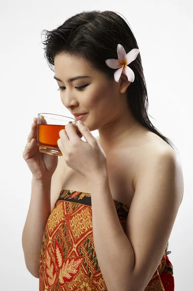 Une femme avec une fleur dans les cheveux tenant une tasse de thé — Photo