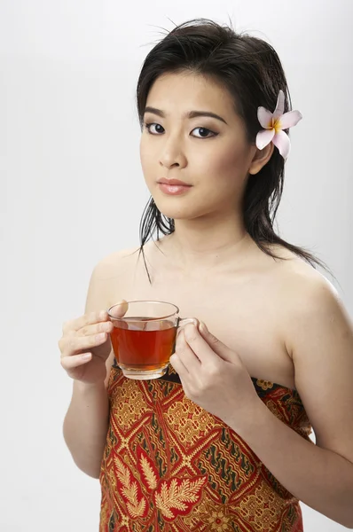 彼女の髪にお茶のカップを保持している花を持つ女性 — ストック写真
