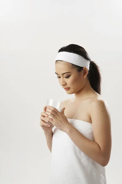 Woman in towel looking to a glass water — Stock Photo, Image