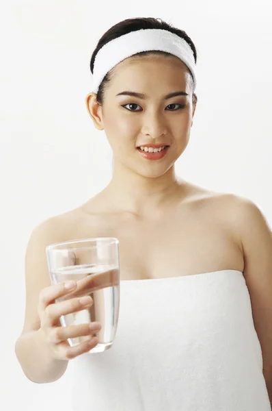 Mulher em toalha mostrar um copo de água limpa — Fotografia de Stock
