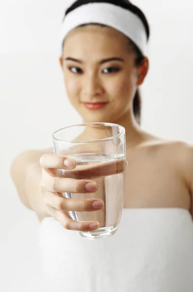Mulher em toalha mostrar um copo de água limpa — Fotografia de Stock