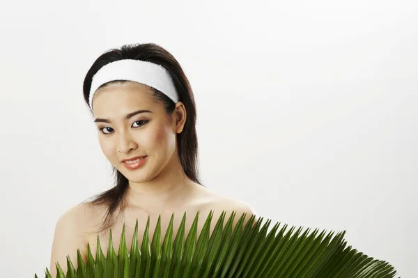 Young woman wearing towel, holding green leaf — Stock Photo, Image