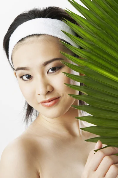 Young woman wearing towel, holding green leaf — Stock Photo, Image