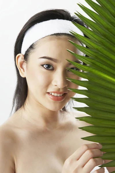 Młoda kobieta sobie ręcznik, trzymając zielony liść — Zdjęcie stockowe