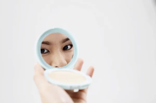 Woman looking in compact mirror — Stock Photo, Image