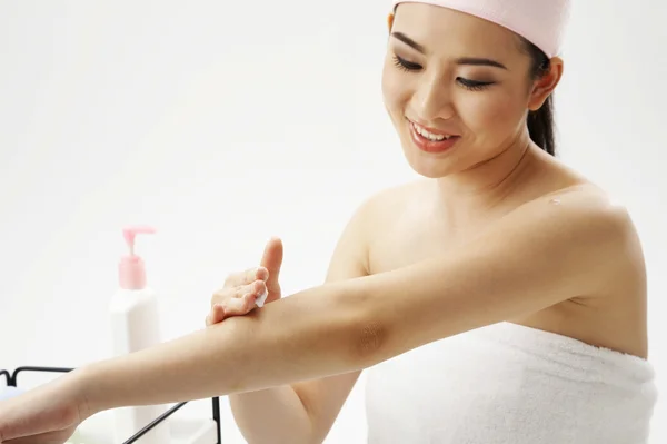Young woman applying lotion — Stock Photo, Image
