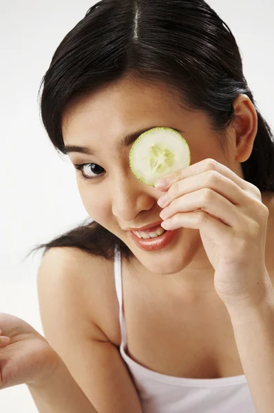 Young Woman Holding Cucumber Slice Over Eye — Stock Photo, Image