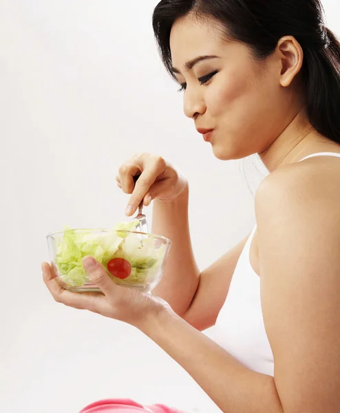 Jovem mulher comendo salada — Fotografia de Stock