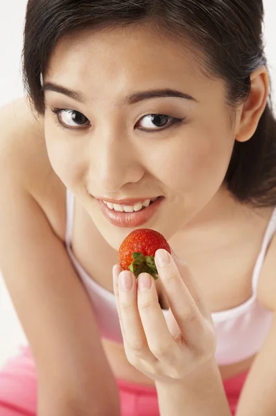 Mladá žena jíst jahody — Stock fotografie