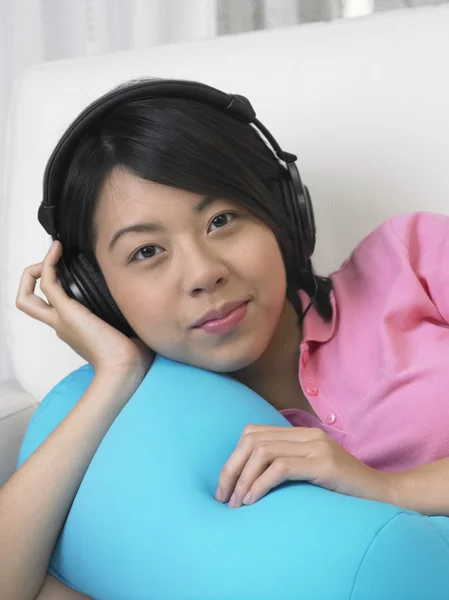 Genç kadın kanepede müzik dinlemek. — Stok fotoğraf