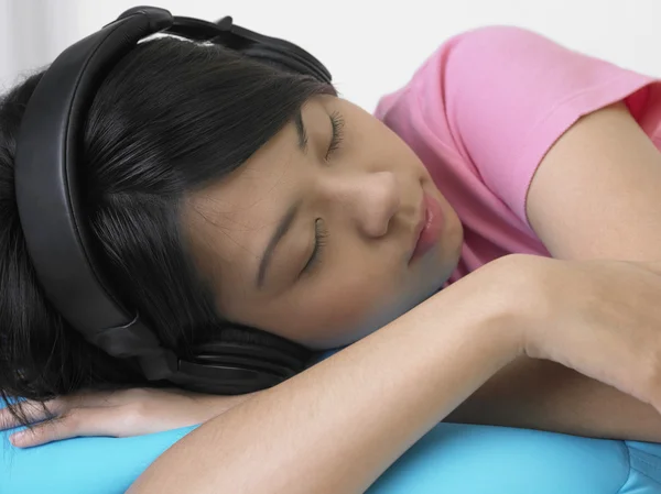 Genç kadın kanepede müzik dinlemek. — Stok fotoğraf