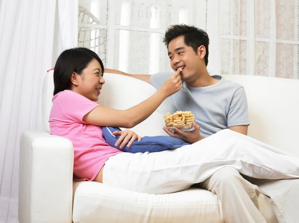 Woman takes a piece of snack from the bowl which her husband is holding — Stock Photo, Image