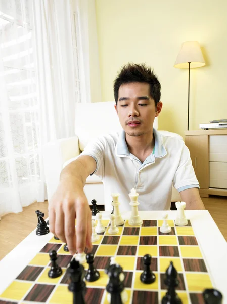 Young man moving his chess piece for his next move — Stock Photo, Image