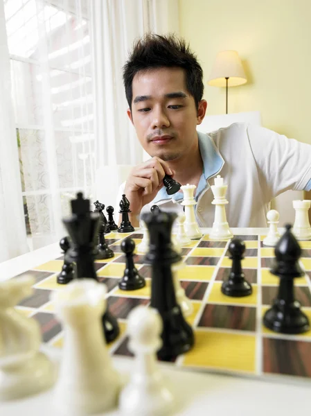 Młody człowiek ruchu jego sztuki szachowy dla jego następny ruch — Zdjęcie stockowe