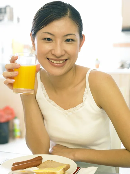Mladá dáma, pití džusu v kuchyni — Stock fotografie