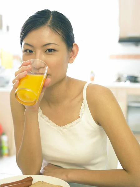 Una giovane signora che beve il suo succo d'arancia in cucina — Foto Stock