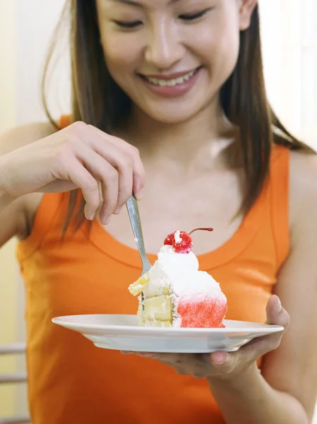 Jovem mulher está saboreando um pedaço de bolo — Fotografia de Stock
