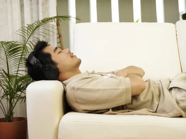 Man ontspannen op de sofa luisteren naar muziek — Stockfoto