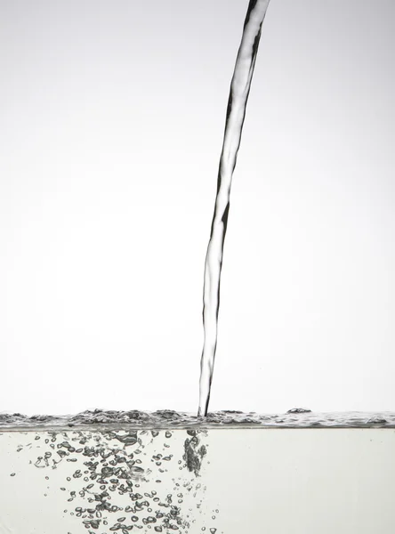 Наливаємо воду в ємність з білим тлом — стокове фото