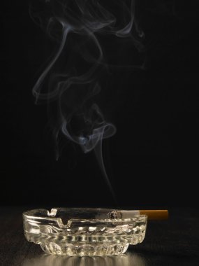 Cigarette with smoke rest on the ashtray clipart