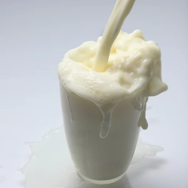 牛乳やカップに白い液体を注ぐ — ストック写真